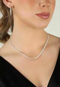 Silverhalsband med glittrande klara stenar, med en slät, böjd design. I kombination med matchande smala hoopsörhängen.