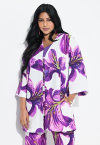 Blomstermønstret kimono i hvid, med store lilla liljemønstre, brede ærmer og en afslappet pasform. Accentueret med en snorelukning.