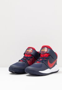 Korfuboots i marinblått och rött, med en texturerad ovandel, ett kardborreband och en vadderad sula med en gummiyttersula för grepp.