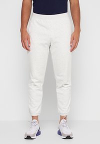 Hellgraue Baumwoll-Jogginghosen mit schmaler Passform, ausgestattet mit einem elastischen Bund und Seitentaschen, kombiniert mit hellen Sneakern.
