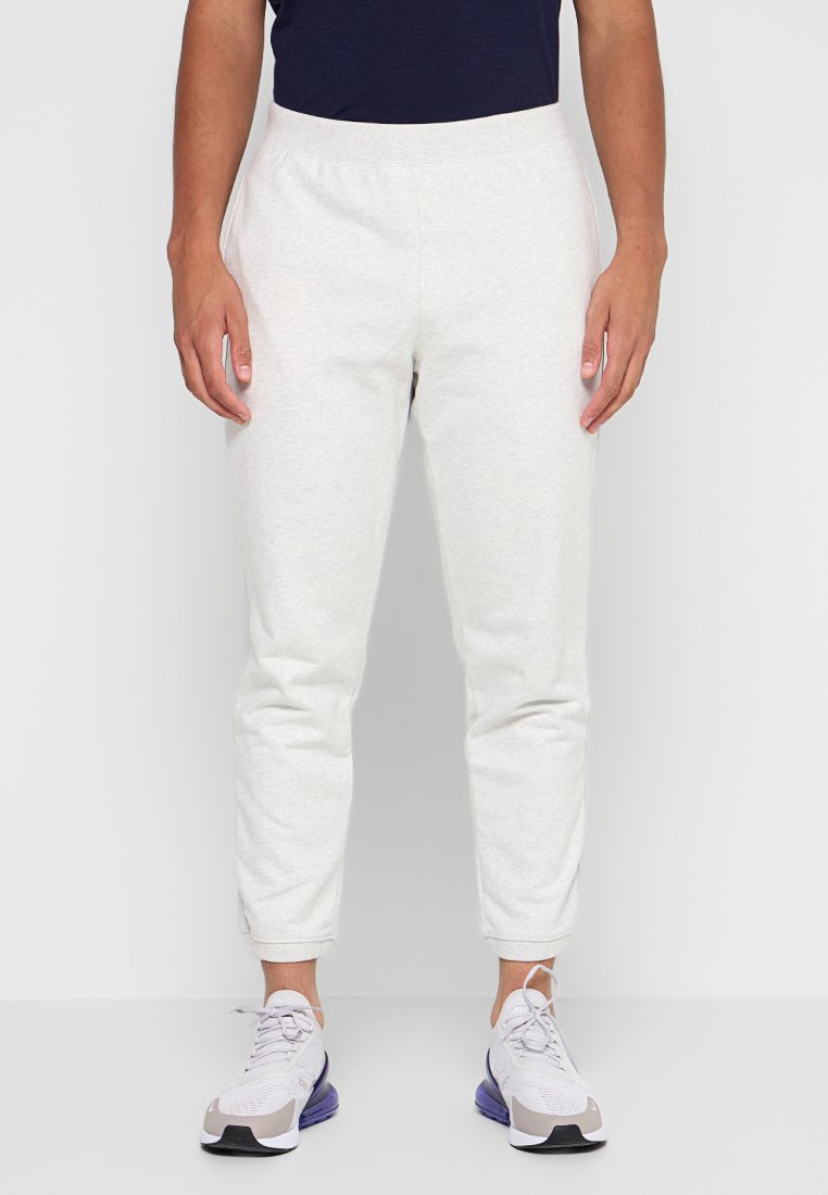 Hellgraue Baumwoll-Jogginghosen mit schmaler Passform, ausgestattet mit einem elastischen Bund und Seitentaschen, kombiniert mit hellen Sneakern.