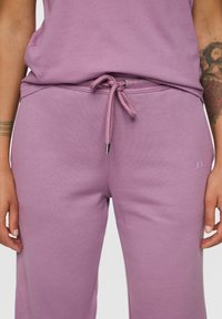 Licht paarse sweatpants met een trekkoord in de taille, elastische boorden en een gestructureerde stof. Heeft een kleine logo-print bij de heup.