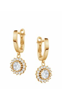 Złote kolczyki w kształcie obręczy mają okrągły kształt z centralnym przezroczystym kamieniem otoczonym mniejszymi, błyszczącymi kamieniami, co tworzy efekt kwiatowy.