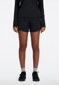 Svarta idrottsshorts med en avslappnad passform och en mjuk textur, tillsammans med en svart långärmad tröja. Bärs med grå strumpor och svarta sneakers.