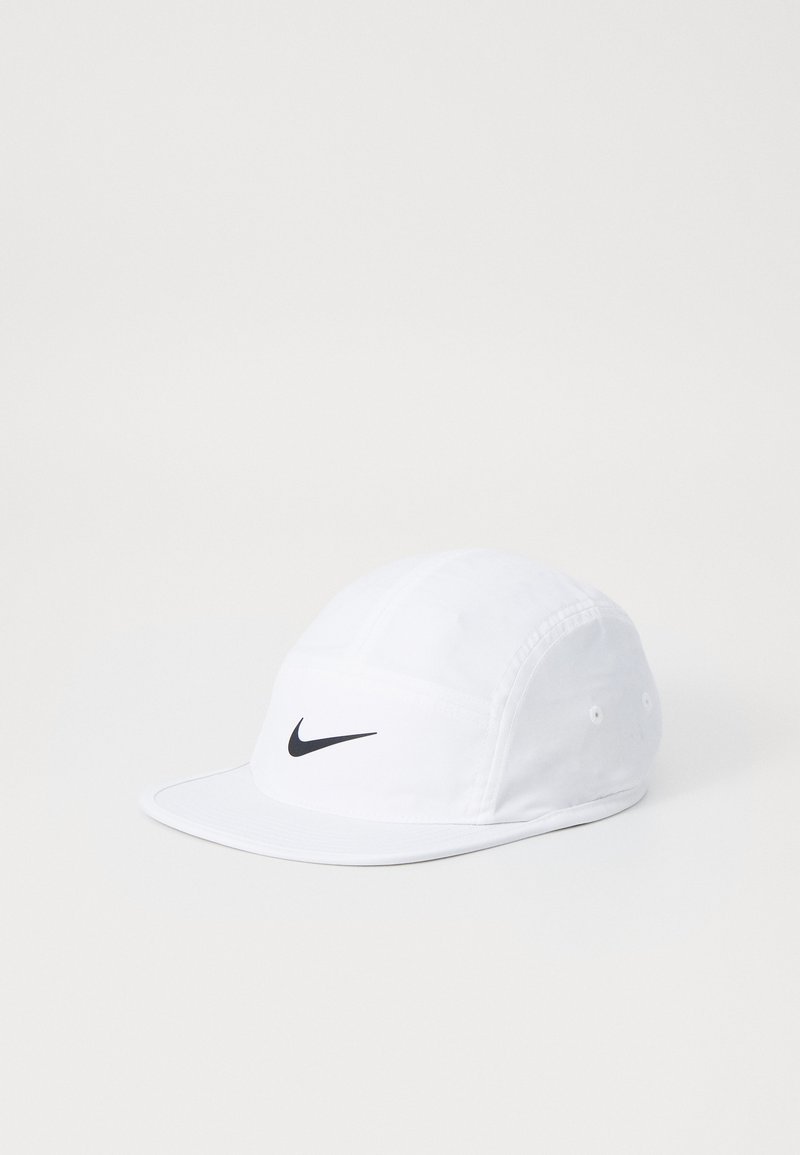 Hvit baseballcaps laget av stoff med en svart Nike swoosh-emblem på fronten. Har en buet skjerm og justerbar stropp bak.