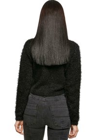 Maglione nero e soffice con maniche lunghe, vita aderente, abbinato a jeans alti grigi scuri con tasche posteriori e finitura testurizzata.