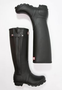 Botas de lluvia negras de goma con suelas texturizadas, cañas altas y detalles de cerradura a presión. Acabado suave, adecuadas para condiciones húmedas.