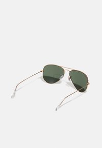 Ochelari de soare aviator cu lentile nuanțate în verde, cadru subțire din metal auriu și vârfuri de temple din silicon transparent. Design clasic și construcție ușoară.