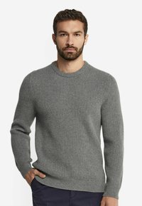 Grå ribbad tröja med rund hals och långa ärmar, med en texturerad stickning och en åtsittande silhuett.