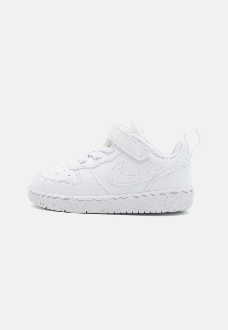 Valkoiset Nike-tennarit, joissa on sileä synteettinen päällinen, tarranauha, nauhaketju edessä ja kumipohja. Pyöristetty kärki ja hienovaraiset perforoinnit.