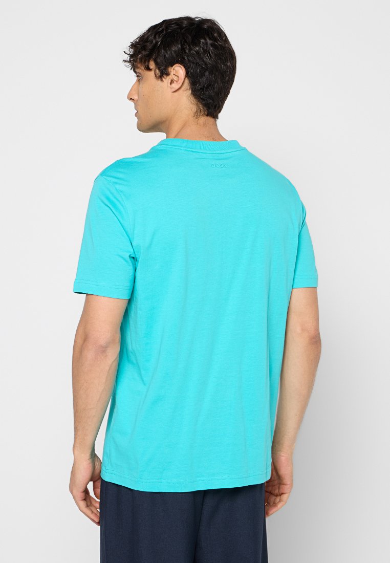 Una maglietta a maniche corte, di colore turchese, realizzata in tessuto morbido, con un design semplice e colletto rotondo, dotata di un logo vicino al collo nel retro.