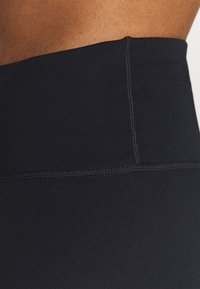 Leggings noirs taille haute avec une texture lisse, dotés de coutures plates et d'une large ceinture élastique pour le confort et la flexibilité.