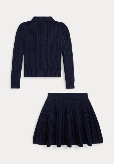 Conjunto de malha em azul marinho, composto por duas peças, apresentando um colarinho canelado e textura em ponto de cable, incluindo um pulôver ajustado e uma saia evasé.