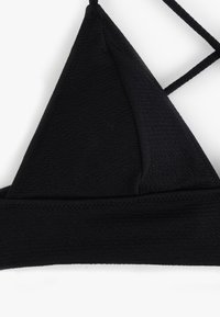 Czarny top bikini z fakturowanej tkaniny, trójkątnymi miseczkami i regulowanymi krzyżującymi się ramiączkami dla pewnego dopasowania.
