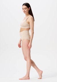 Beige sømløs bh med én justerbar strop og højtaljede trusser, begge med en glat, strækbar stof og minimalistisk design.