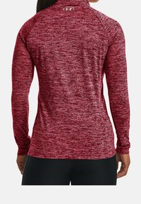 Top sportivo a maniche lunghe in tessuto rosso melange, caratterizzato da un collo alto e un logo posteriore. Texture liscia con design aderente ed elasticizzato.