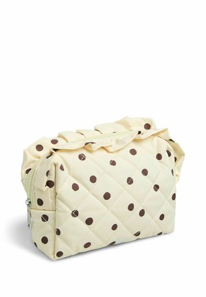 Trousse de maquillage crème matelassée avec des pois marron, bord supérieur froncé et fermeture éclair, posée sur un fond blanc.