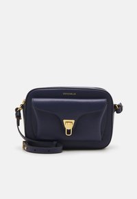 Dunkelblaues Leder-Crossbody-Bag mit strukturiertem Finish, goldfarbener Beschlag, Vordertasche und verstellbarem Trageriemen. Markenlogo sichtbar.