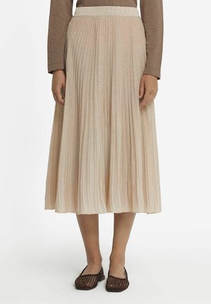 Plisserad midikjol i en mjuk beige nyans, med en texturerad tyg och ett elastiskt midjeband. Bärs med mörkbruna vävda slip-on skor.
