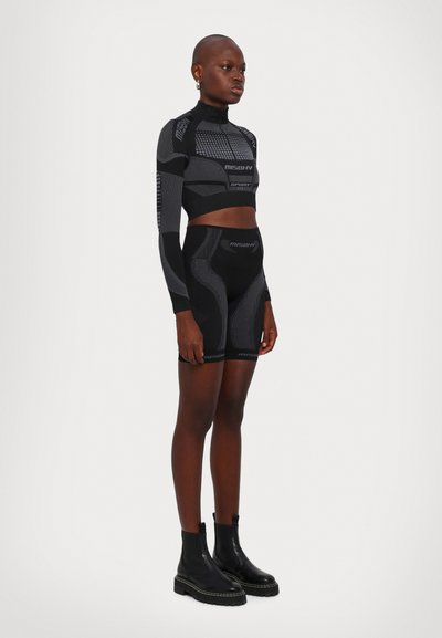 Black sports set with long-sleeve cropped top and high-waisted shorts featuring textured geometric patterns. Accented with zip closure.