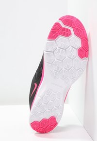 Sneaker nera con tomaia texturizzata e accenti rosa. La suola presenta un motivo esagonale in bianco e rosa, che migliora la presa e la flessibilità.