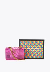 Sac bandoulière matelassé transparent rose avec une bandoulière chaîne dorée à côté d'une boîte colorée et à motifs de la marque Kurt Geiger London.