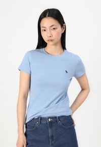 Light blue short-sleeve t-shirt made of cotton. Features a small embroidered logo on the chest and a classic crew neckline.