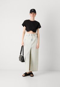 Fekete rövidített póló, világos farmer maxi szoknya elöl hasítékkal, fekete válltáska és fekete slip-on szandál. Egyszerű dizájn és laza megjelenés.