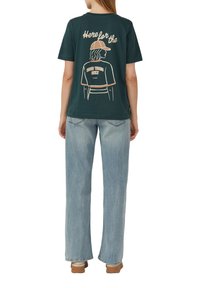 T-shirt en coton vert foncé avec un dessin linéaire d'une personne portant une casquette et le texte "Ici pour les bons moments seulement" en rose et blanc.
