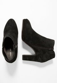 Bottines en suède noir avec un bout pointu, fermeture éclair latérale et un talon bloc de 3 pouces. Texture lisse avec un design moderne et une apparence minimaliste.