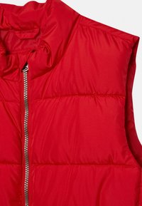 Rote Steppweste mit Stehkragen, silbernem Reißverschluss und ge quilteter Textur. Verfügt über eine glatte Außenfläche und ein leicht gepolstertes Design.