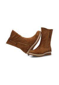 Botas de tobillo de ante marrón con cremallera lateral, puntera redonda y suela texturizada. Presentan un diseño ligeramente arrugado y una suela clara en contraste.
