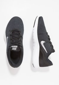 Scarpe sportive nere con tomaia in mesh, logo Nike bianco e suola bianca leggera. Presentano chiusura con lacci e dettagli testurizzati.