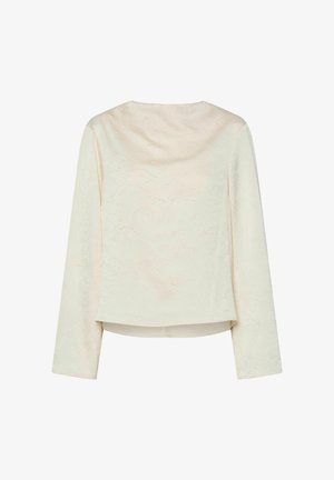 Kremfarget topp med lange ermer, som har et strukturert stoff og et drapert utringning. Nederst er den cropped med en svak nedoverbakke bak.