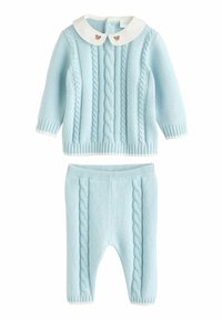 Lichtblauwe gebreide tweedelige outfit. Het truitje heeft een kabelpatroon, een ronde witte kraag met berenknopen. Bijpassende gebreide broek met kabelpatroon.