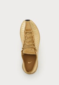 Smeđi Nike Air tenisice s zavezicama od nubuka i perforiranim stranama, prikazane odozgo na običnoj bijeloj pozadini.