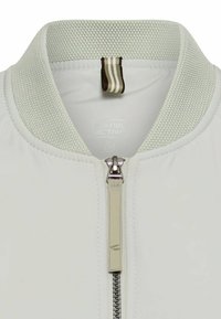 Lysecreme bomberjakke med en tekstureret mesh-krave, metalknap og subtil branding. Har et glat, vandafvisende stof.