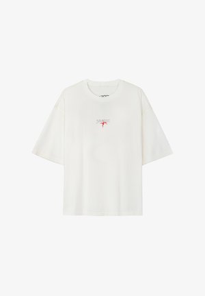 Biała, bawełniana, oversize'owa koszulka z krótkimi rękawami, okrągłym dekoltem i czerwonym haftem na piersi.