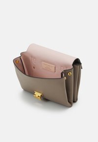 Leather handbag with a taupe exterior and soft pink interior, featuring a gold clasp and multiple compartments for organization.