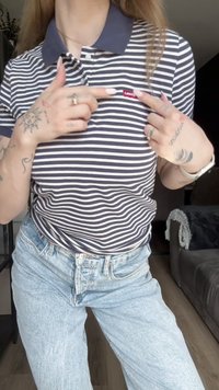 Randig polo i marinblått och vitt, med en krage och en röd Levi's-logotyp på bröstet; tillsammans med ljusblå jeans.