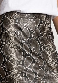 Zwart-grijze slanghuidrok met een textuurovervlak, een aansluitend ontwerp en een gladde afwerking, met diamantvormige patroonaccenten.