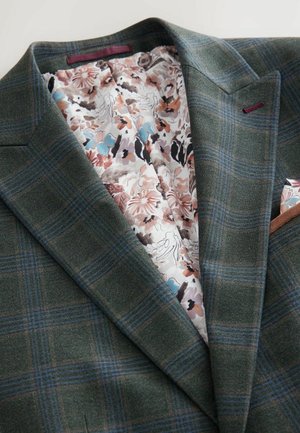 Blazer de cuadros verdes con un exterior de lana texturizada. Forrado con tela de estampado floral que presenta acentos en rosa, azul y negro.