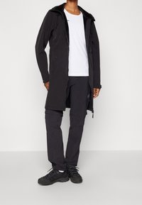 Black long jacket with a hood, zip front, and adjustable drawstrings, paired with black pants and dark shoes. Features a simple design.