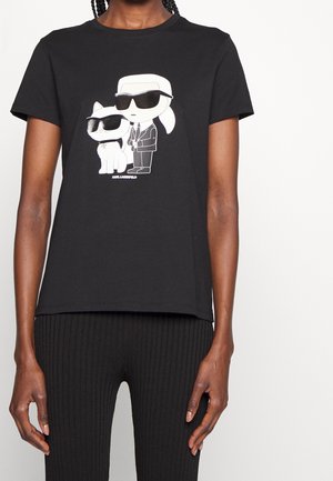 Sort bomulds-T-shirt med motiv af to tegneseriefigurer iført solbriller. Korte ærmer, rund hals, afslappet pasform.