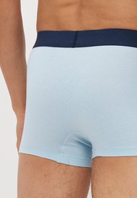 Ljust blå bomullsboxershorts med ett marinblått elastiskt midjeband. Har en figurnära design och en sömlös baksida för komfort och stöd.