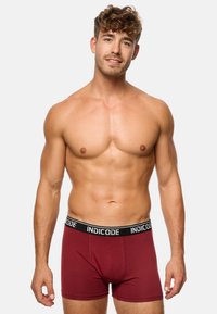 Boxeri maronii dintr-un material elastic, având un elastic negru cu logo-ul "INDICODE". Design ajustat cu o textură fină.