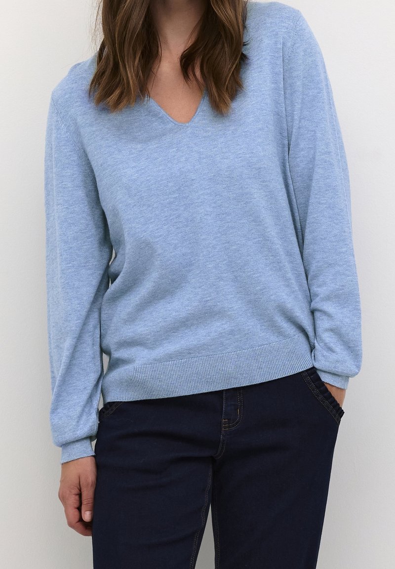Light blue V-neck sweater made of soft knit material with long sleeves and ribbed hem, paired with dark jeans.