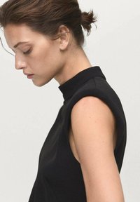 Black sleeveless top with a high neck, featuring structured shoulders and a smooth fabric texture. Side profile view of model.