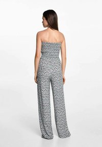 Grijze, strapless jumpsuit met een smock-borstvoordeel, wijde pijpen en een luipaardprint in zwart en donkerblauw. Zachte stoftextuur.