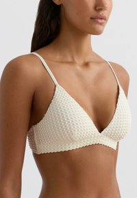 Krém színű háromszög szabású bralette texturált anyagból, vékony vállpántokkal, puha, kötött mintával és sima alsó szegéllyel.